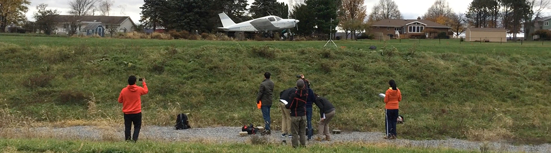 Students take outdoor noise measurements on a small runway.   